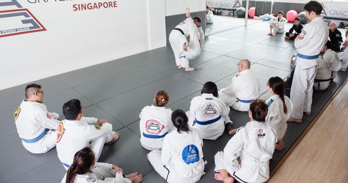 Adult students watching a coach demonstrate a technique during a Gi class at GJJ Singapore