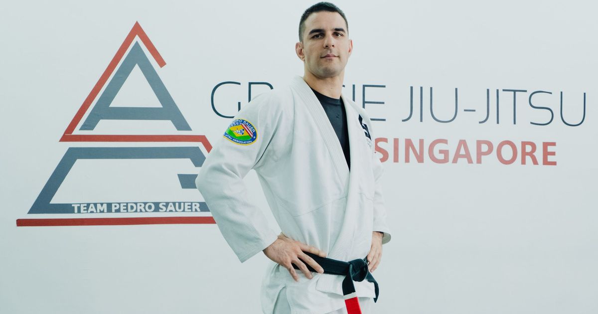 A Gracie Jiu-Jitsu Singapore black belt instructor on the mat in front of the academy logo