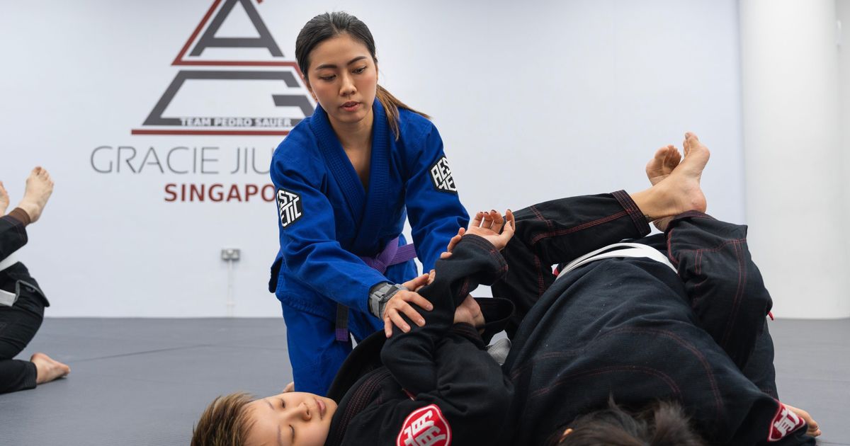 A female purple belt coaching a training partner's technique at Gracie Jiu-Jitsu Singapore